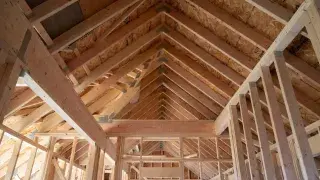 Roof framing interior showing rafters, ridge line, and supporting wall framing inside a wood-framed house.