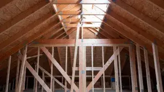 Roof framing and supporting wall structure inside a wood-framed house under construction.