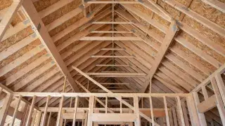 Wood roof framing interior showing rafters, ridge line, and wall framing carrying roof loads.