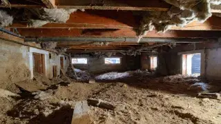 Neglected crawl space with bare soil, exposed vents, and hanging insulation.