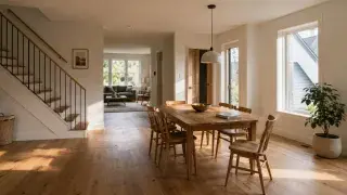 Modern open-plan home interior with soft natural light across a dining area, stair, timber floor, and connected living space.