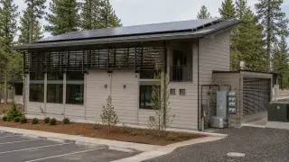 Low-energy building with rooftop solar panels, exterior shading, high-performance windows, and visible mechanical service equipment for net zero architecture.