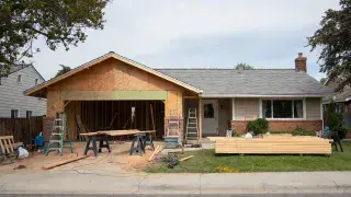 Ranch house with a front garage addition under construction and driveway materials on site.