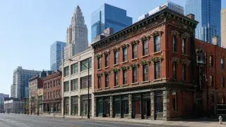 Historic red-brick commercial buildings standing in front of Art Deco and modern glass towers in an American city.