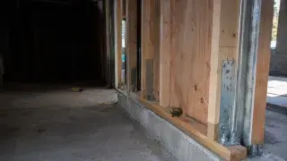 Seismic retrofit framing with plywood shear panels, hold-down anchors, and concrete foundation.