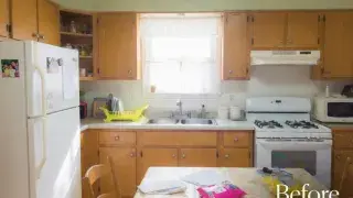 Worn midcentury kitchen with wood cabinets, white appliances, and a crowded dining table.