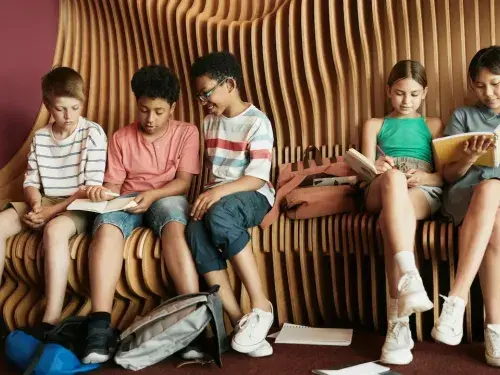 Kids sitting on a bench with architectural design, engaging in a hands-on learning experience about architecture.