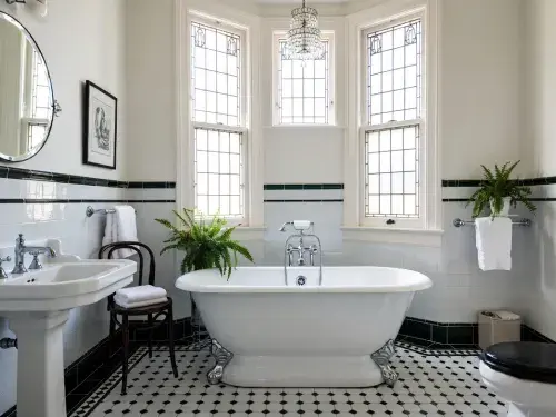 Authentic-style 1930s bathroom with clawfoot tub, pedestal sink, wall tile, and mosaic floor.