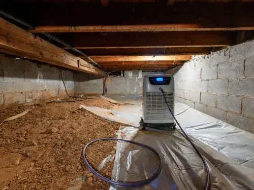 Crawl space dehumidifier running beside exposed soil and a partial ground liner.