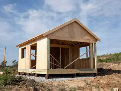 Small workshop frame raised on piers above gravel instead of a full concrete pad.