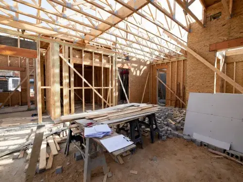 Residential construction site showing wooden framing, foundation, and structural layout.