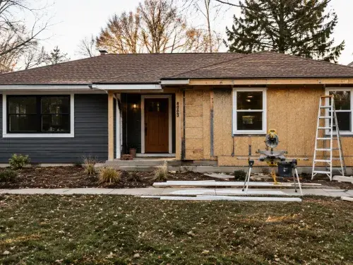 Ranch house exterior renovation with new siding on one side and exposed wall sheathing on the other.