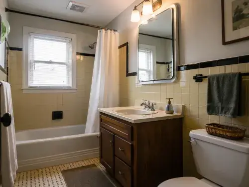 1950s bathroom remodel with original wall tile, updated vanity, improved lighting, and practical finish upgrades.