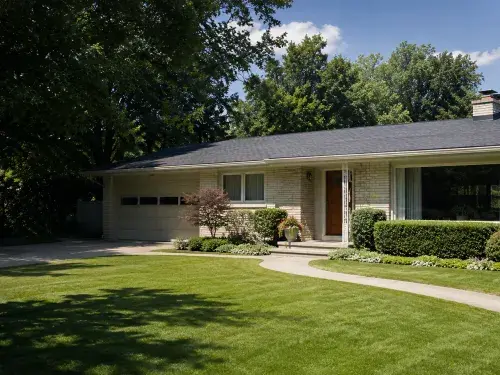 1950s ranch house with light brick, long low roofline, attached garage, picture window, shaded lawn, and mature trees.