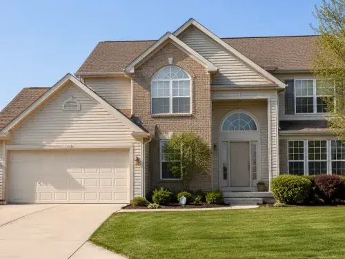 Typical 1990s suburban house with brick, vinyl siding, front garage, gables, and arched windows.