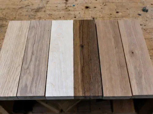 Six unfinished hardwood samples on a worn cabinetmaker’s bench.