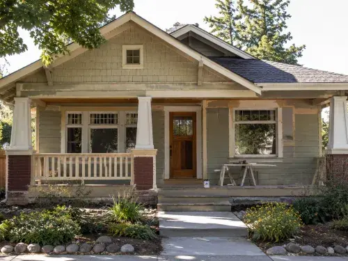 Old Craftsman house with front porch, wood trim, and early renovation work.