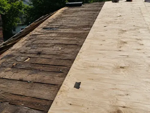 New plywood sheathing installed over old roof planks during a reroof repair.