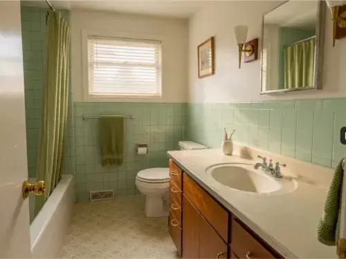 Original mid-century ranch bathroom with mint tile and wood vanity.