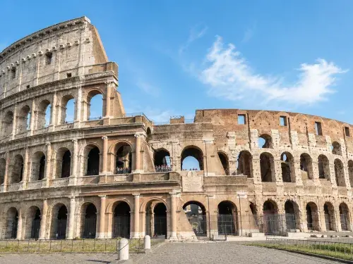 Bright daytime view of the Roman Colosseum and its weathered exterior arches.