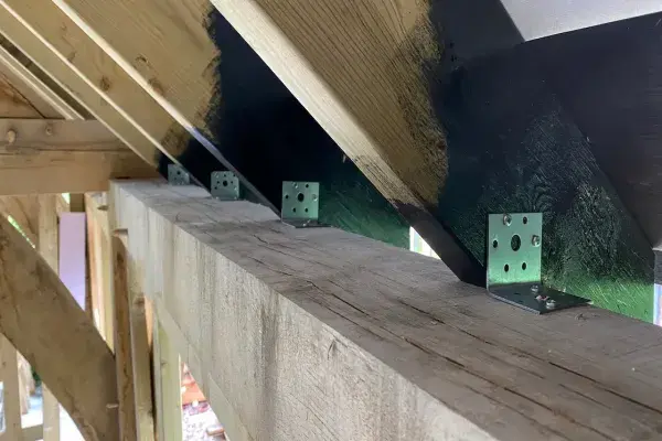 Metal rafter braces installed in a house under construction, providing structural support for the roof framework.