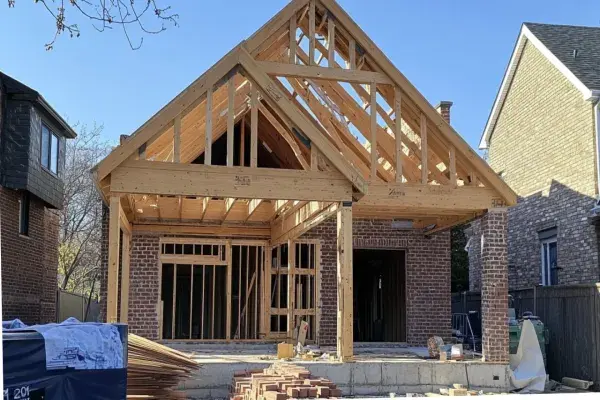 A residential house under construction with a partially completed wooden frame using prefabricated timber trusses.