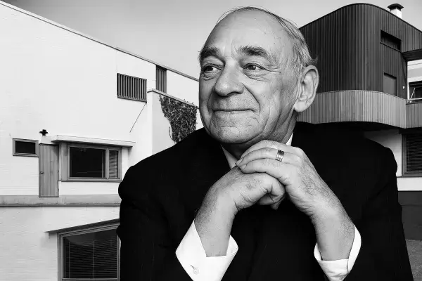 Portrait of Alvar Aalto with one of his architectural works behind him, reflecting his modernist approach that harmonizes design with the surrounding environment.