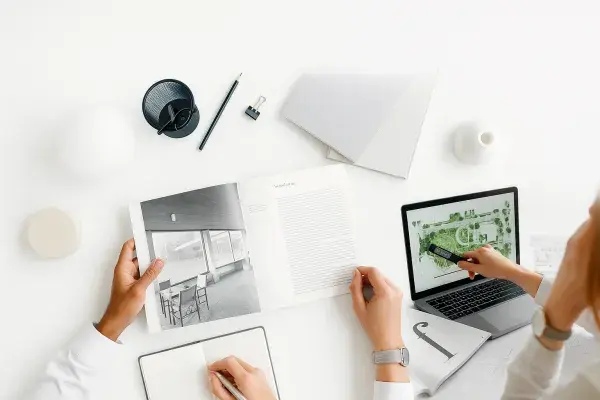 A workspace with architecture book, laptop, and tools.