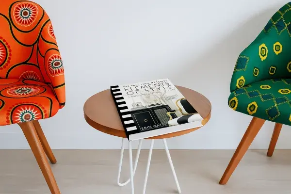 Book “Elements of Style” lying on a table between two colorful chairs.