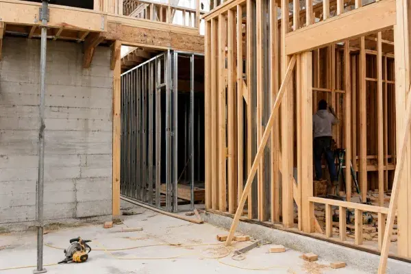Construction site with concrete structure, steel stud framing, and wood framing visible together.