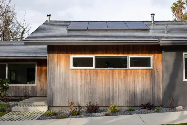 Renovated older house facade with upgraded windows, durable cladding, and clean energy-conscious detailing.