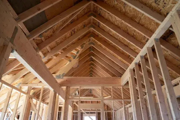 Roof framing interior showing rafters, ridge line, and supporting wall framing inside a wood-framed house.