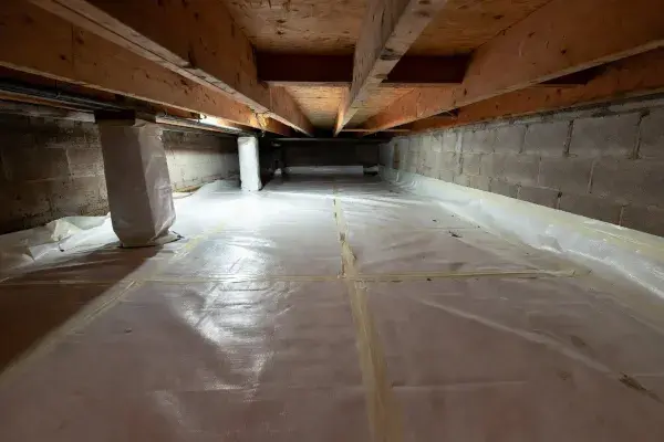 Installed crawl space vapor barrier with taped seams, wall turn-up, and wrapped piers.