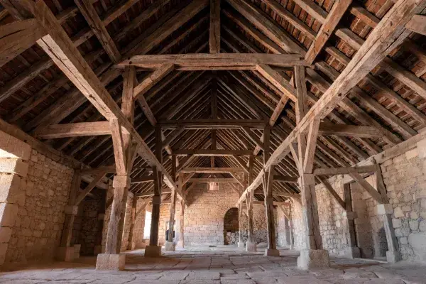 Historic timber hall with a hammer beam roof opening above a large stone interior.