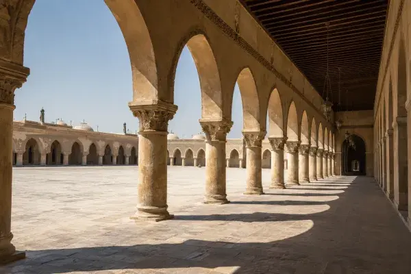 Islamic arcade with repeated stone arches casting shade across a courtyard walkway.