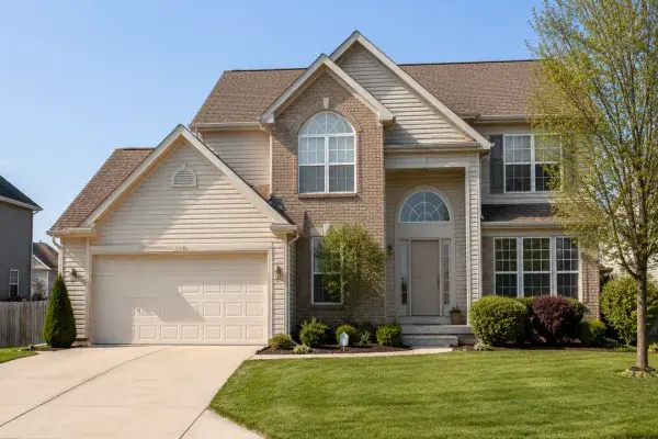 Typical 1990s suburban house with brick, vinyl siding, front garage, gables, and arched windows.