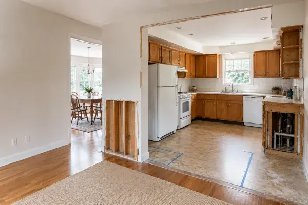 A ranch kitchen remodel with an opened wall, exposed patching, soffit, and floor transition.
