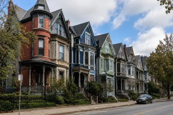 Street of Victorian houses with steep rooflines, bay windows, porches, tall windows, and decorative trim.